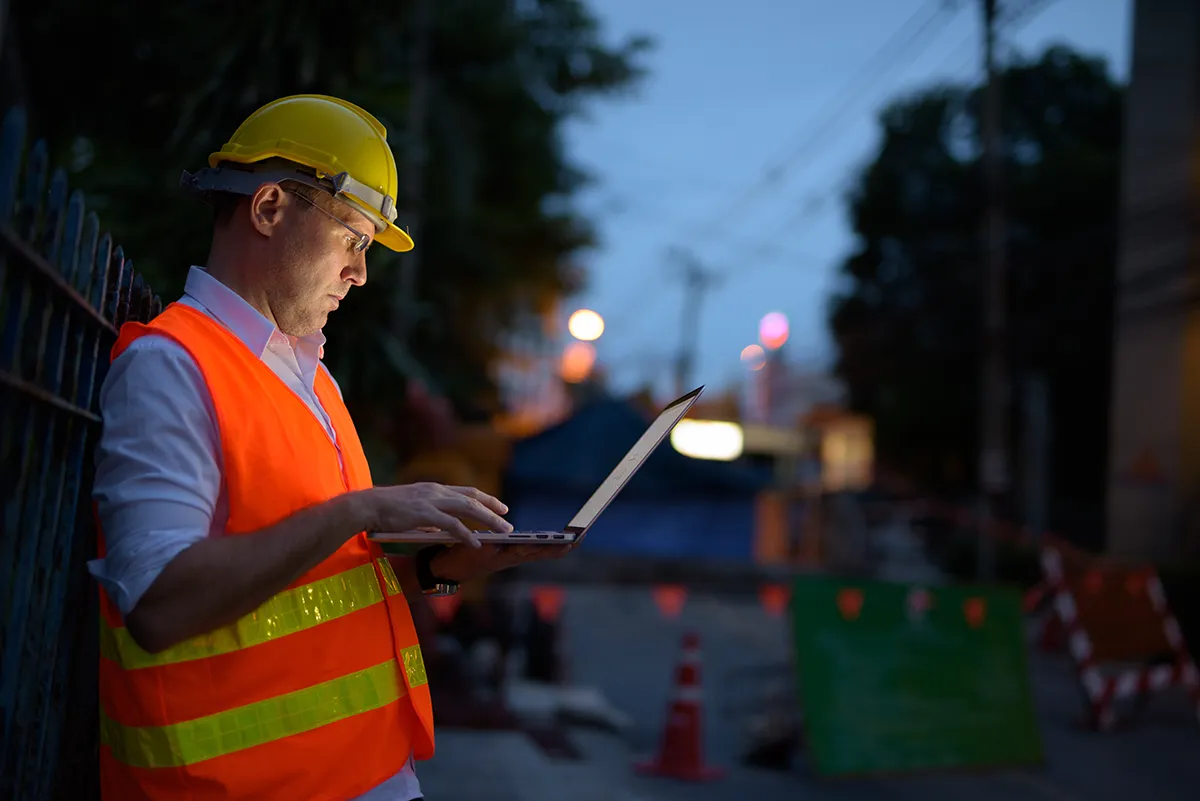 A civil construction engineer working on a laptop on a construction site in Melbourne