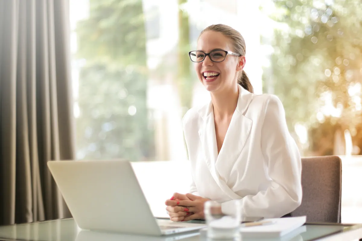 A lawyer sitting at her desk with a smile on her face, looking at her laptop